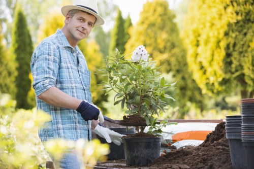 Worker in PPE performing safe landscaping waste collection in Woolwich